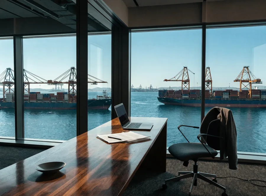 A trade desk overlooking a container port at dusk.